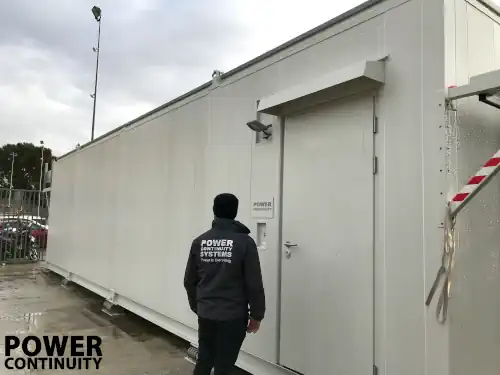 Power continuity engineer in front of white containerised data centre